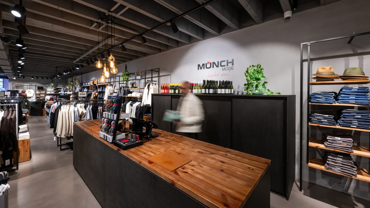 Theke mit Holzplatte vor dem Münch-Mode-Logo