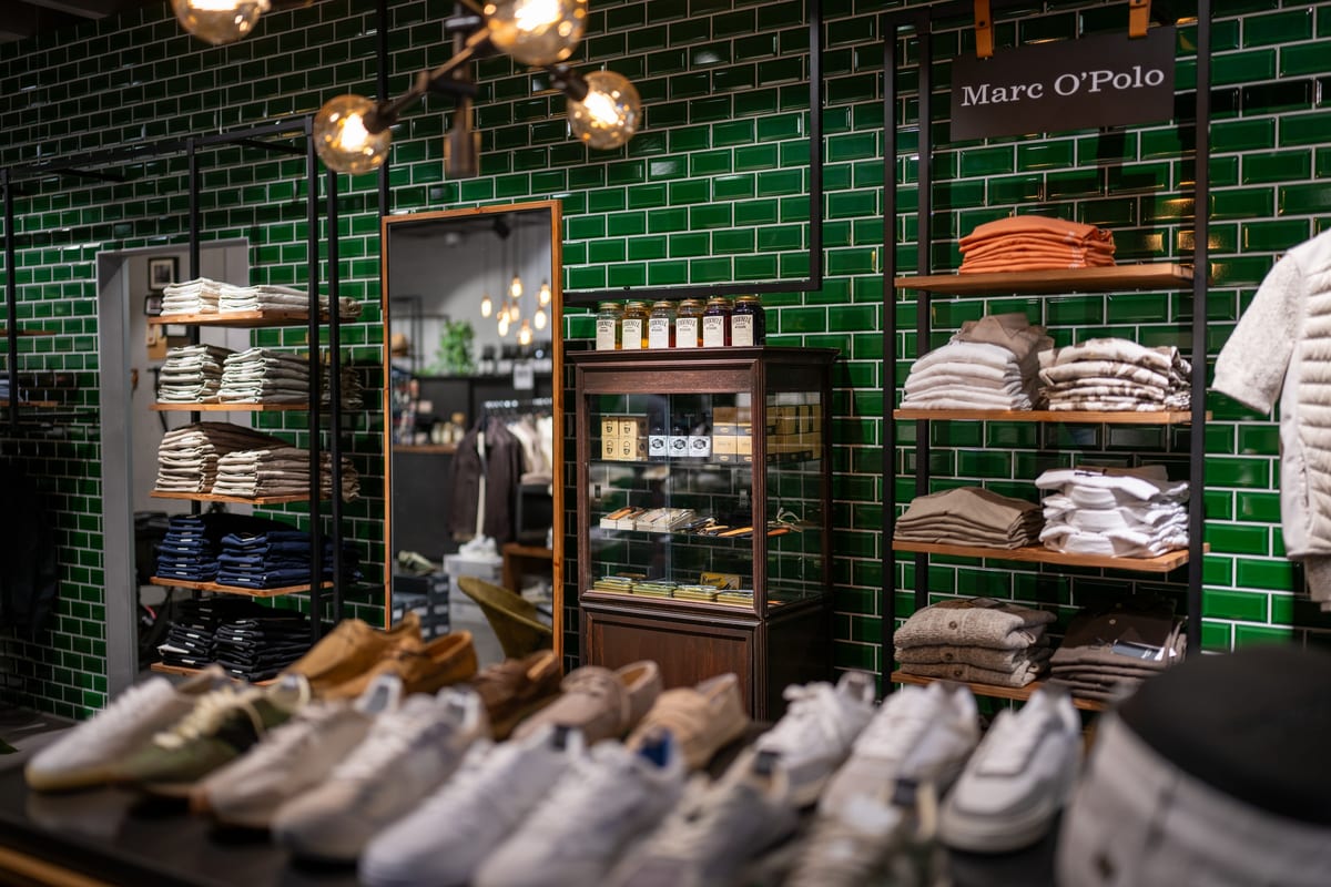 Marc O'Polo vor grün gefliester Wand, Sneaker im Vordergrund